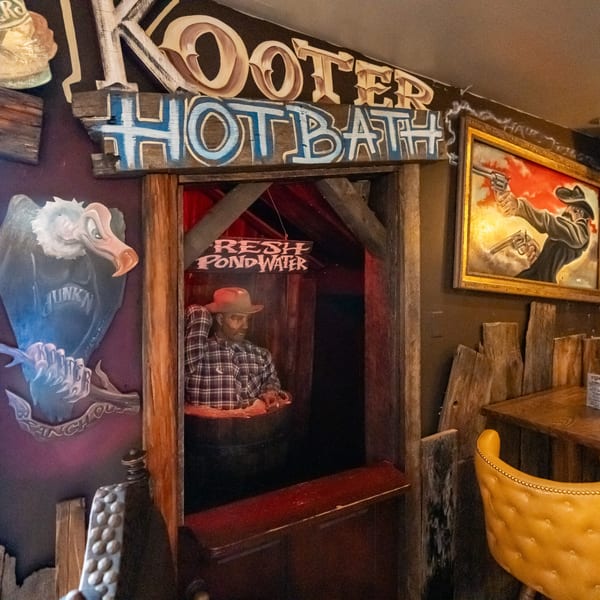 Krazy Kooters' quirky interior with a cowboy mannequin in a barrel and a vulture mural.