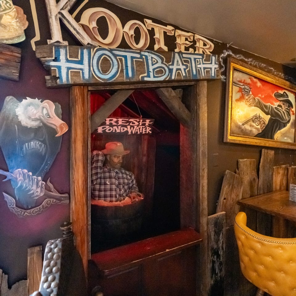 Krazy Kooters' quirky interior with a cowboy mannequin in a barrel and a vulture mural.