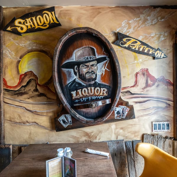 Western-themed wall art at Krazy Kooters, featuring a cowboy on a barrel, saloon signs, and playing cards.