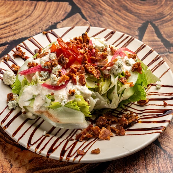 Krazy Kooters' wedge salad with bacon, blue cheese, tomatoes, and red onions, drizzled with balsamic glaze.