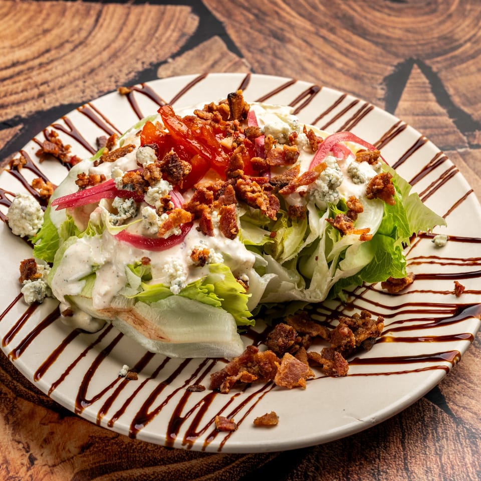 Krazy Kooters' wedge salad with bacon, blue cheese, tomatoes, and red onions, drizzled with balsamic glaze.