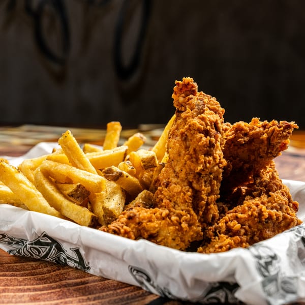 Crispy fried chicken tenders and golden french fries in a paper-lined basket from Krazy Kooters.