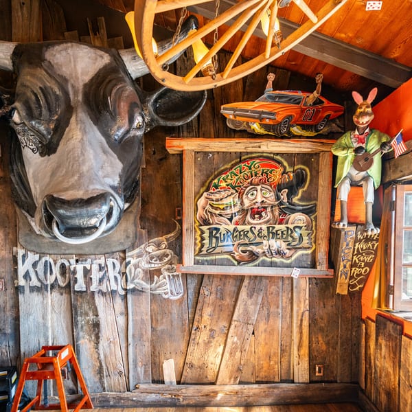 Krazy Kooters restaurant interior with a large cow head, a "Burgers & Beers" sign, and a rabbit playing a banjo.