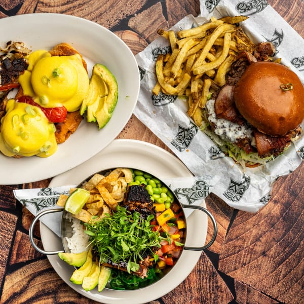 A Krazy Kooters burger with fries, eggs benedict, and a rice bowl with salmon and vegetables.