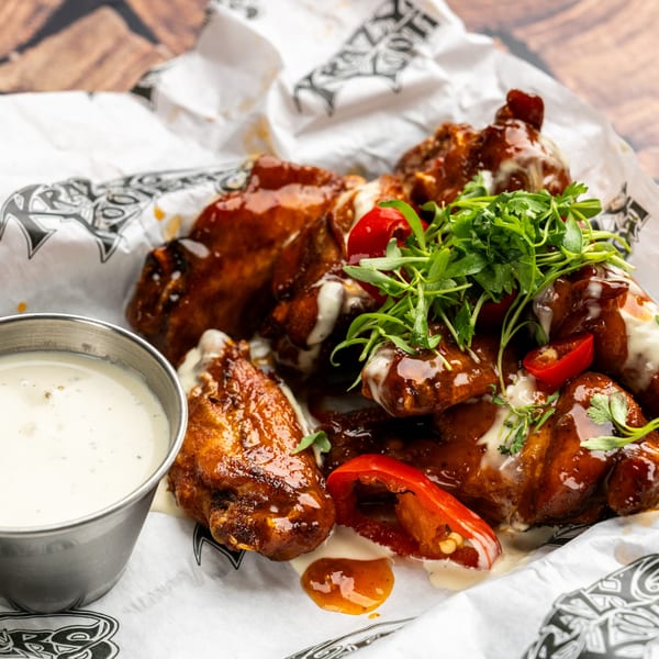 Krazy Kooters' BBQ chicken wings with ranch, red peppers, and cilantro on branded paper.
